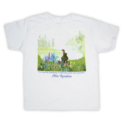 White t-shirt with an illustration of Miss Rumphius as she kneels down to admire a crop of lupine flowers against a coastal Maine landscape
