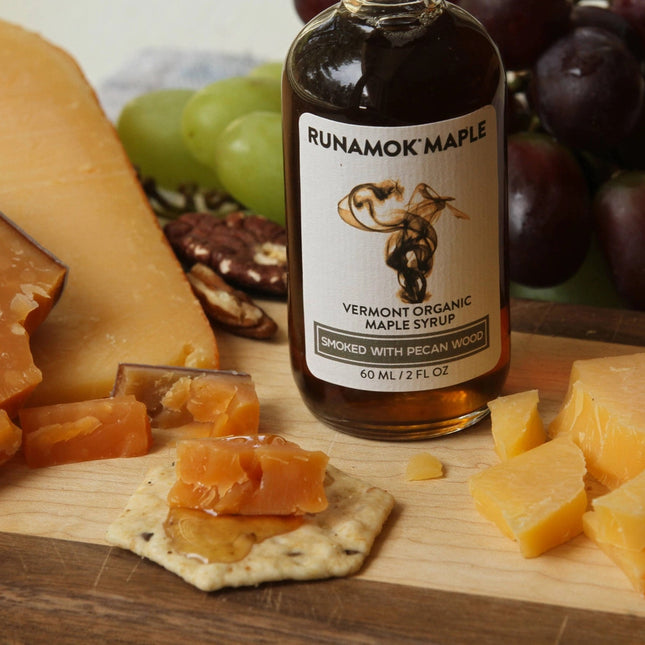 a bottle of smoked maple syrup on a cheese board with cheese and crackers to show how to pair the syrup with cheese