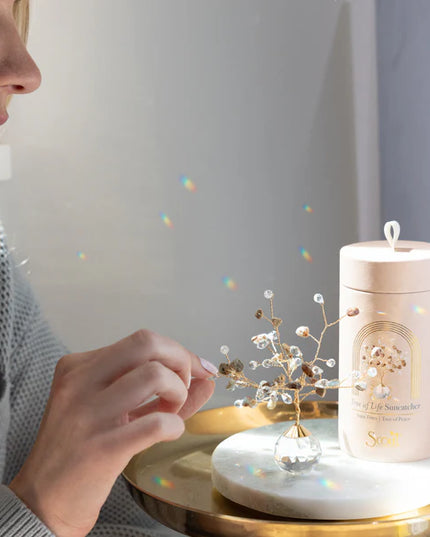 a model arranging the branches on her tree of life suncatcher on a sunlight side table