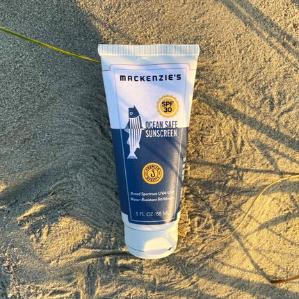 a blue and white sunscreen bottle on a sandy beach