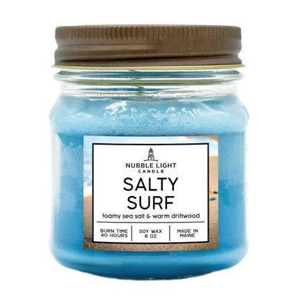a sky blue candle in a mason jar with brown lid and text on the label that reads "Salty Surf: foamy sea salt & warm driftwood"
