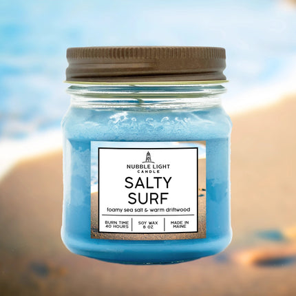 The Salty Surf candle jar shown against a beach background