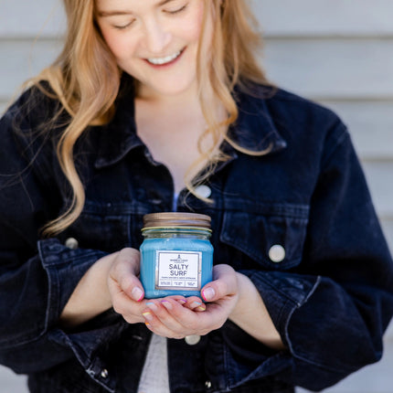 a model cradling a Salty Surf candle in her hands