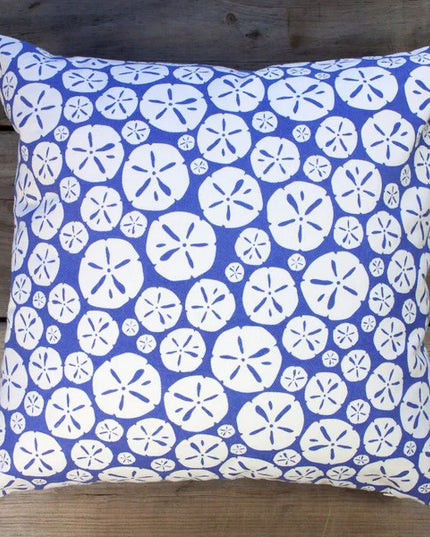 cornflower blue pillow with repeated sand dollar design on a wood surface