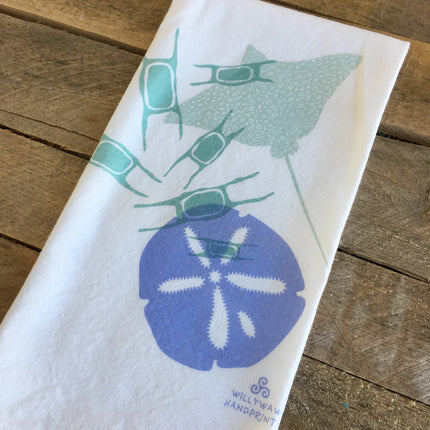 White towel with blue sand dollar and green sea urchin design on a wooden surface
