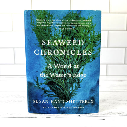 Book titled 'Seaweed Chronicles' by Susan Hand Shetterly on a white brick background