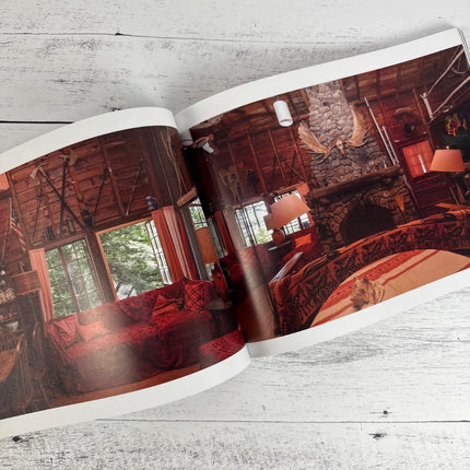 Open book showing a rustic interior design with wooden walls and red accents.