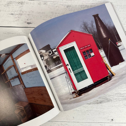 Open book showing a red shed with a green door on a snowy landscape.