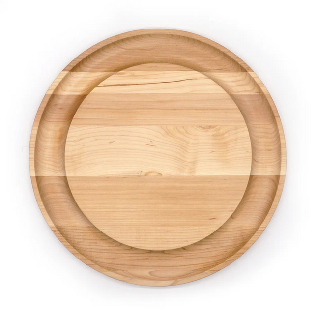 A round maple serving board with a well for crackers on the outer edge