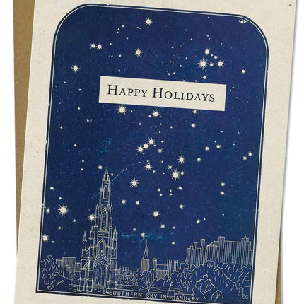 a close up look of the details of an off white greeting card that reads "Happy Holidays" with a vintage illustration of a city with a navy blue sky of stars shining above it, the bottom of the plate reads "southern sky in january"