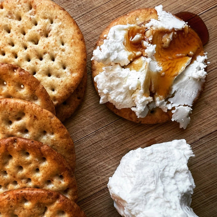 Crackers with a spread of cream cheese and spruce syrup on a wooden surface
