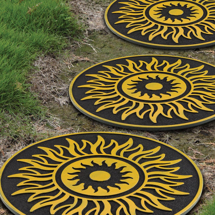 Three round black and yellow sun-shaped outdoor stepping stones arranged on a grassy lawn.
