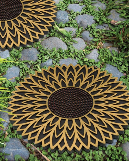 two garden stepping stones with sunflower design installed in a stony garden pathway 