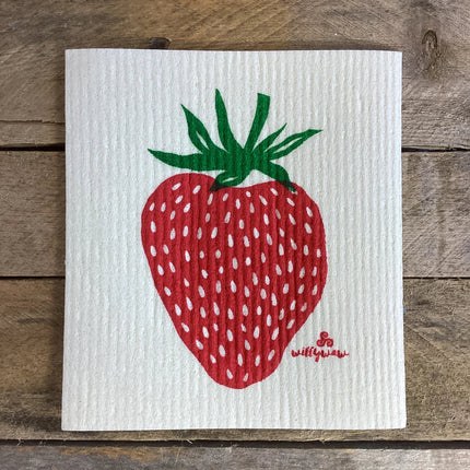 a white, rectangular dish cloth with a large hand printed strawberry illustration in red and green