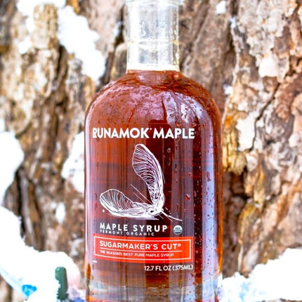 a bottle of sugarmaker's cut resting on a maple tap on a snowy maple tree