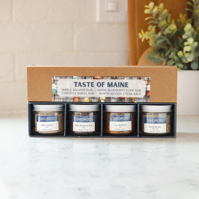 Box of Skordo Spice Jars with 'Taste of Maine' branding on a marble surface.