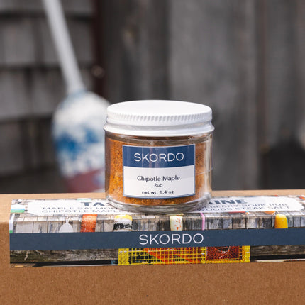 Jar of Skordo Chipotle Maple Rub on a cardboard box with blurred background