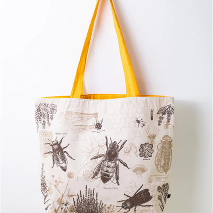 side one of the honey bee tote; a white tote bag with yellow straps covered in vintage illustrations and academic diagrams of the honey bee