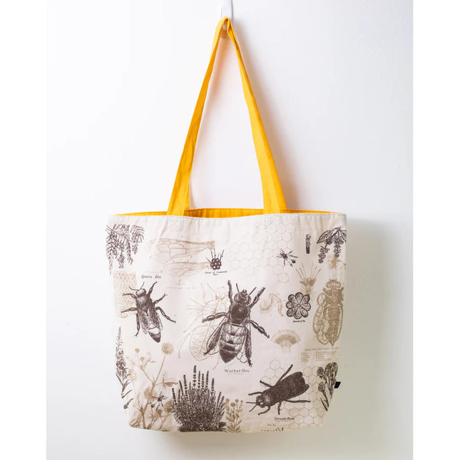 side one of the honey bee tote; a white tote bag with yellow straps covered in vintage illustrations and academic diagrams of the honey bee