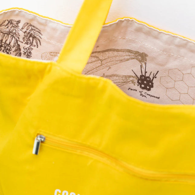 a close up of the tote near the handles showing the bag reversed so the honey bee print is on the inside of the tote and the outside is now a goldenrod yellow