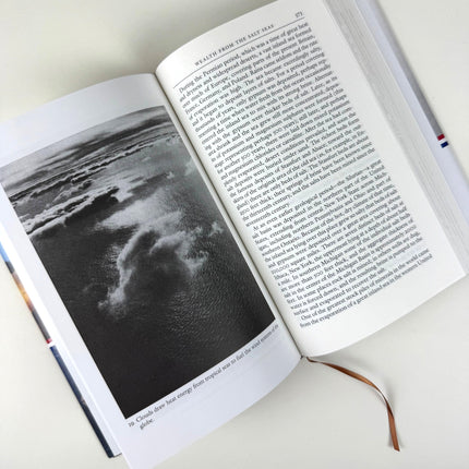 Open book with a black and white photograph of an aerial view of the sea and clouds with text on a light background