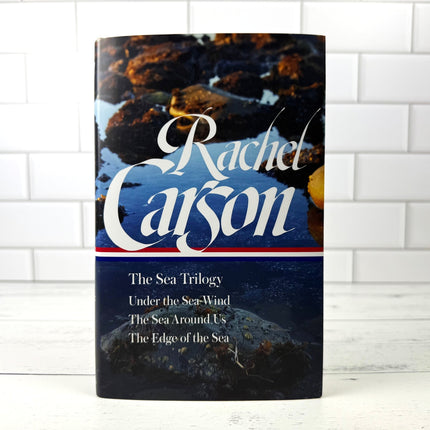 Book titled 'The Sea Trilogy' by Rachel Carson on a white tiled background