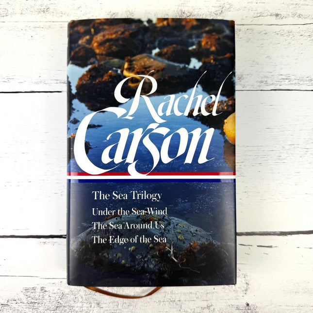 Book titled 'The Sea Trilogy' by Rachel Carson on a wooden surface