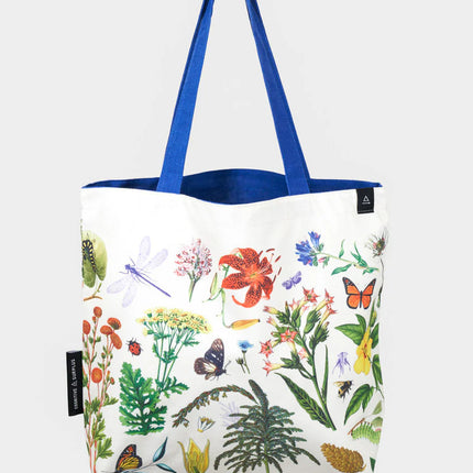 side two of the pollinator tote; a white tote bag with blue straps covered in vintage illustrations of hummingbirds, bees, butterflies, and the plants they pollinate