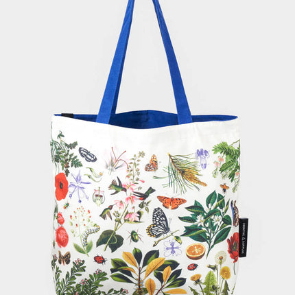 side one of the pollinator tote; a white tote bag with blue straps covered in vintage illustrations of hummingbirds, bees, butterflies, and the plants they pollinate