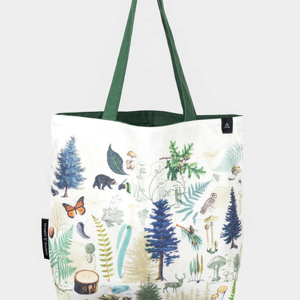 side one of the into the woods tote; a white tote bag with forest green straps covered in vintage illustrations of woodland flora and fauna