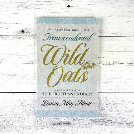 Book cover of 'Transcendental Wild Oats' by Louisa May Alcott on a wooden surface
