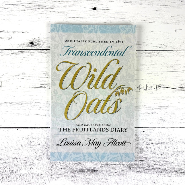 Book cover of 'Transcendental Wild Oats' by Louisa May Alcott on a wooden surface