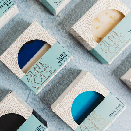 Atlantic Soap Co. soap bars in open boxes on a textured surface