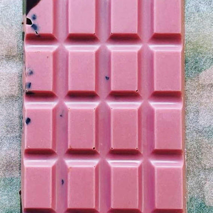 an unwrapped Ursa Major bar showing the brilliant pink hue of the raspberry white chocolate with swirls of dark chocolate and cacao nibs visible