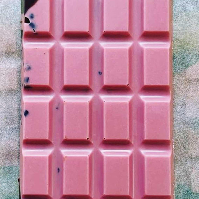 an unwrapped Ursa Major bar showing the brilliant pink hue of the raspberry white chocolate with swirls of dark chocolate and cacao nibs visible