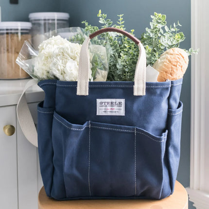 Blue tote bag with flowers and plants on a wooden surface