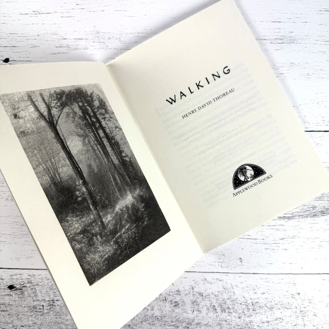 Open book titled 'Walking' by Henry David Thoreau on a wooden surface