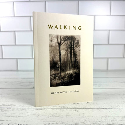 Book titled 'Walking' by Henry David Thoreau on a wooden surface with a tiled wall background