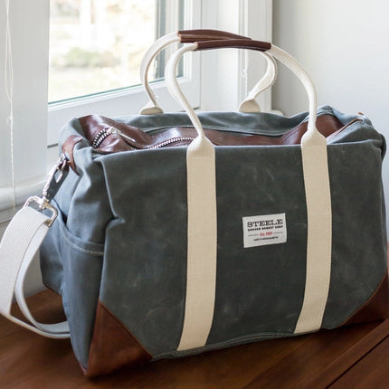 the waxed briquette weekender bag all packed next to a door, ready for adventure