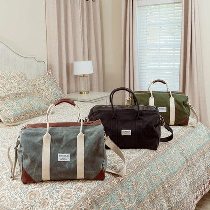 a hotel room bed with the 2 weekender bags lined up on it