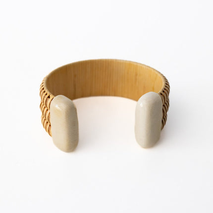 Wooden bracelet with a textured band and smooth ends on a white background