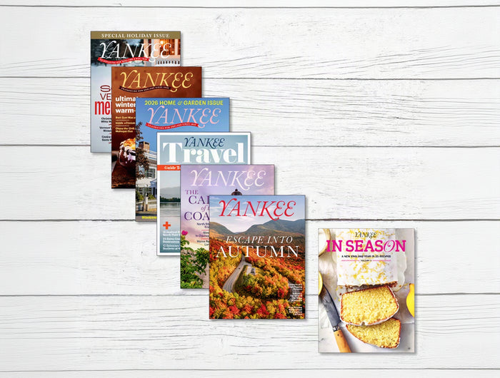 A fan arrangement of five Yankee Travel magazine issues on a white wood background, with a sixth magazine cover titled 'In Season' placed to the right.