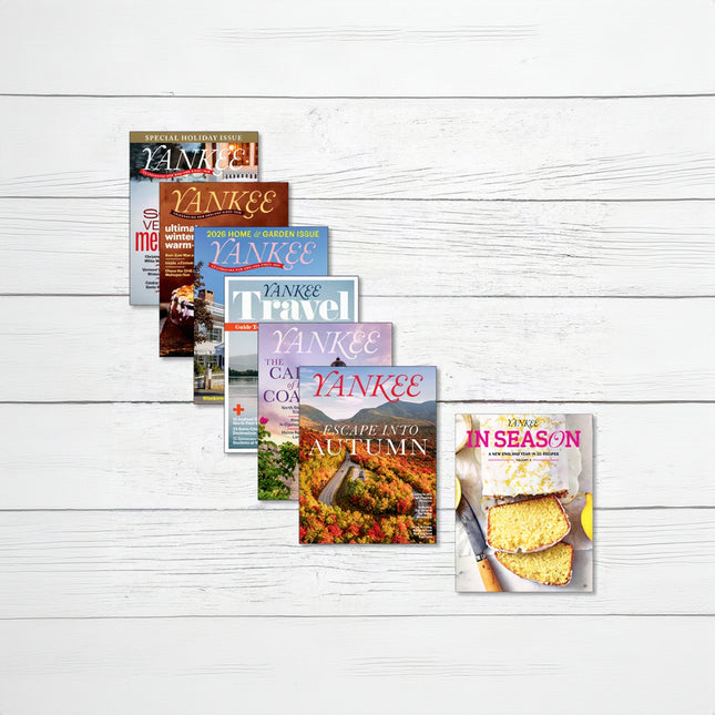 A fan arrangement of five Yankee Travel magazine issues on a white wood background, with a sixth magazine cover titled 'In Season' placed to the right.