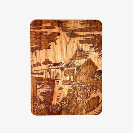 Wooden cutting board with engraved design of a covered bridge over water