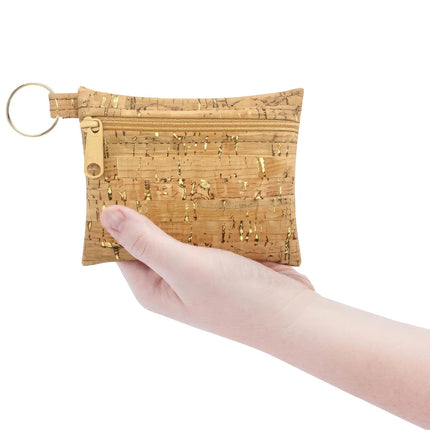 Hand holding a cork pouch with a key ring on a white background
