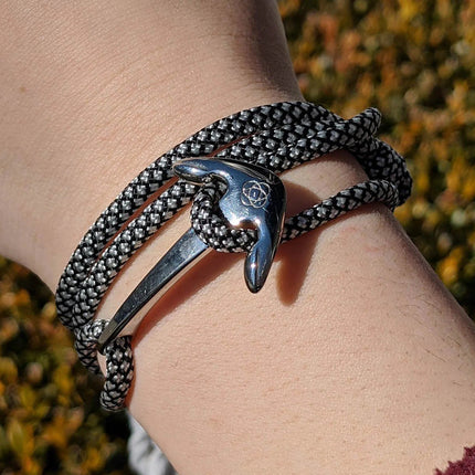 a black with white diamond pattern cord wrap bracelet with silver anchor charm on a model