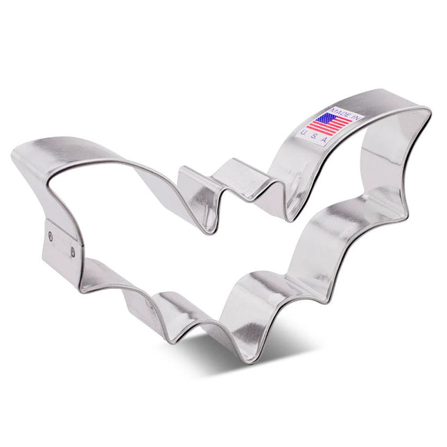 A tin cookie cutter in the shape of a flying bat with wings spread