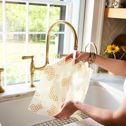 a woman rinsing her bee's wrap under a kitchen sink