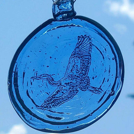 a light blue, round glass suncatcher with a relief image of a heron