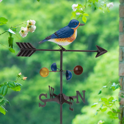 close up of Bluebird weathervane stake displayed in a garden setting, surrounded by  greenery
